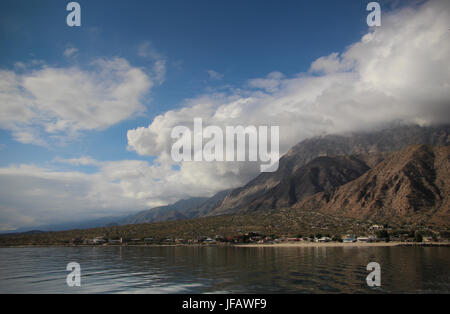 Blick auf Los Angeles Bucht in Baja California Norte aus dem Wasser; garniert mit weißen Wolken, blauer Himmel, erheben schroffe Berge sich hinter dem Dorf, Stockfoto