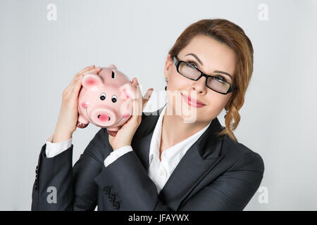 Schönes Lächeln auf den Lippen Geschäftsfrau schütteln Sparschwein Überprüfung Geldbetrag. Banking, Insuarance und Geld Kapital Konzept. Stockfoto