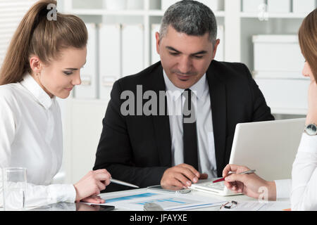 Erwachsenen Kaufmann consulting seine junge Kollegin während Geschäftstreffen. Partner, die Dokumente und Ideen diskutieren Stockfoto