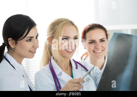 Porträt von drei weiblichen Medizin Ärzte betrachten Röntgenbild lächelnd. Gesundheitswesen und Medizin-Konzept. Stockfoto