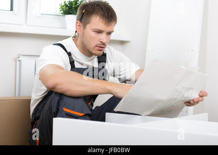 Frustriert Mann Anleitung lesen und Selbstmontage Möbel zusammenstellen. DIY, neue Heimat und bewegende Konzept Stockfoto