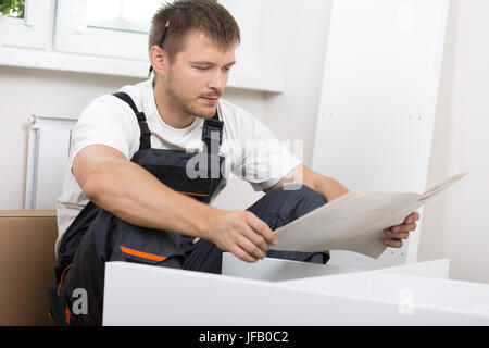 Frustriert Mann Anleitung lesen und Selbstmontage Möbel zusammenstellen. DIY, neue Heimat und bewegende Konzept Stockfoto