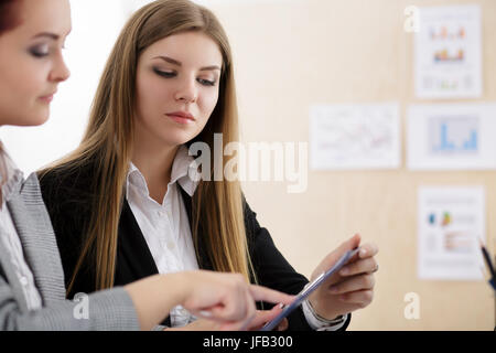 Zwei Frauen sitzen im Büro und mit Blick auf die Diagramme und Tabellen einige Fragen diskutieren. Finanzielle Planung, Buchhaltung, irs, Präsentation oder Geschäft Stockfoto