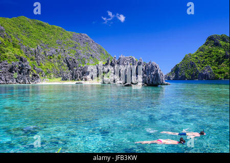 Touristen, die Schwimmen im kristallklaren Wasser im Bacuit Archipel, Palawan, Philippinen Stockfoto