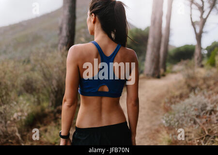Rückansicht des jungen asiatischen Frau zu Fuß auf Bergweg. Gesunde weibliche Läufer in der Sportswear auf Kreuz Feldweg. Stockfoto