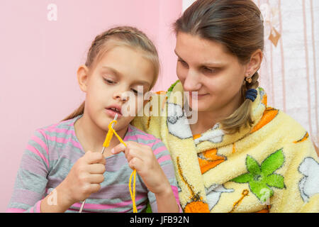 Mutter lehrt Tochter zu sieben Jahren stricken Stockfoto