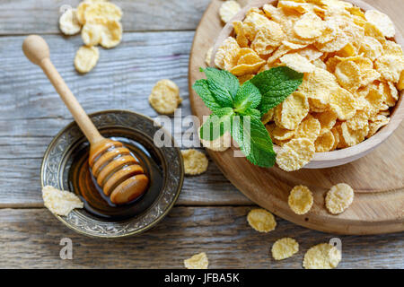 Cornflakes mit Honig und einem Zweig Minze. Stockfoto