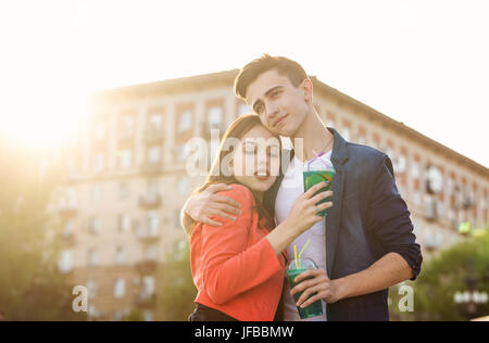 Jugendliche trinken Obst frisch aus Gläsern. Sie umarmen sich. Ein Liebespaar auf ein Datum. Romantik der ersten Liebe. Stockfoto