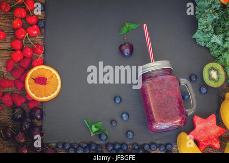 Frischer Smoothie berry gesundes Getränk im Glas mit Speisekarte auf schwarzem Stein, Retro-getönt Stockfoto