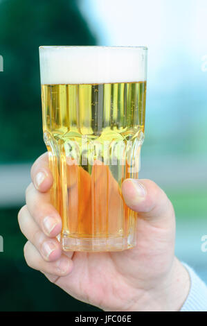 Des Menschen Hand mit einem Glas helles Bier. Stockfoto