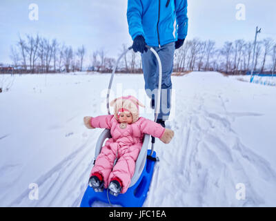 Das Kind geht im Winter auf dem Schlitten. Gehen Sie mit den Eltern. Stockfoto