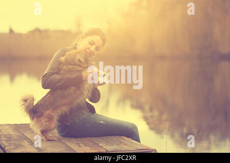 Frau mit Hund am See im Sonnenuntergang Stockfoto