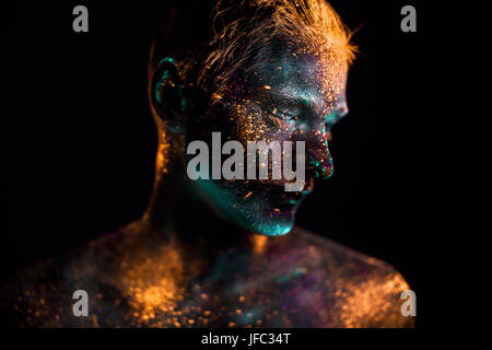 Konzeptionelle Schuss von Licht und Glanz fluoreszierende Farben des jungen Mannes Gesicht Stockfoto