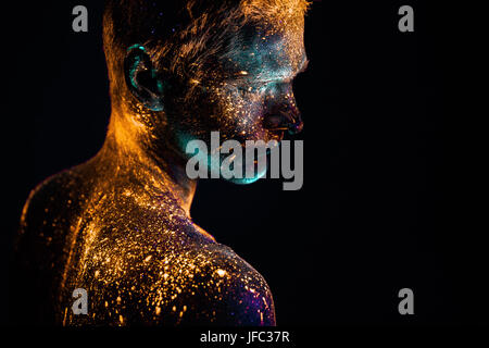 Konzeptionelle Schuss von Licht und Glanz fluoreszierende Farben des jungen Mannes Gesicht Stockfoto