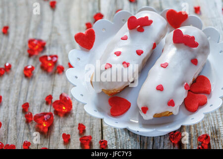 Eclairs mit Dekor der Herzen auf einem weissen Metall stehen. Stockfoto