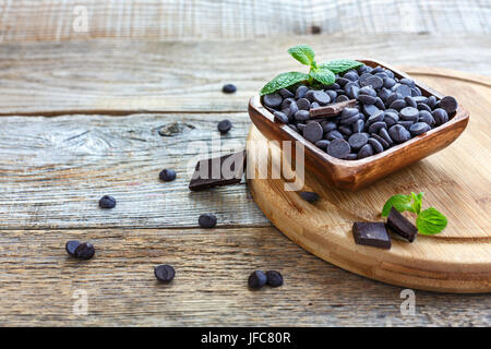 Schüssel mit schwarzer Schokolade auf einem hölzernen Schneidebrett. Stockfoto