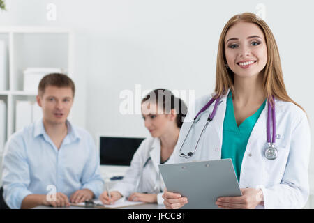 Porträt des Lächelns weibliche Medizin Arzt mit ihrer Kollegin Beratung männliche Patienten im Hintergrund. Gesundheitswesen und Medizin-Konzept. Stockfoto