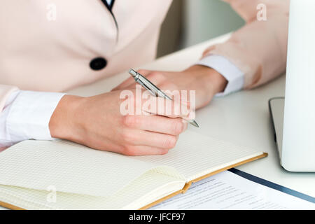 Weibliche Hand Holding Silberstift Nahaufnahme. Frau schreiben, Brief, Liste, Plan, Notizen, Hausaufgaben zu machen. Online-Fernausbildung, freiberuflich, selbst deve Stockfoto