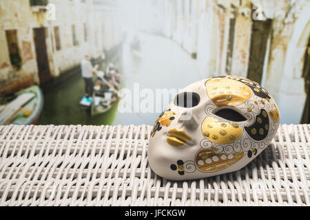 Maske aus Venedig mit einem Gondoliere Rudern eine Gondel in einem engen Kanal in den unscharfen Hintergrund. Golden und ornamentalen Souvenir in Italien. Stockfoto