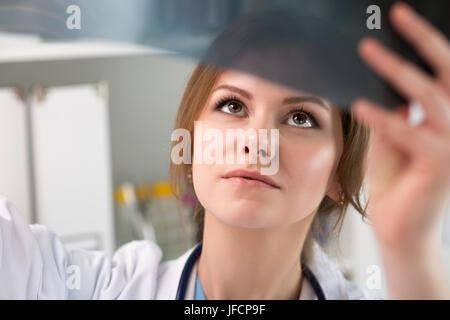 Junge Ärztin sucht im Röntgenbild der Lunge. Gesundheitswesen und medizinische Konzept Stockfoto