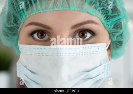 Close-up Portrait von jungen weiblichen Chirurgen Arzt oder Praktikant Schutzmaske und Hut tragen. Gesundheitswesen, medizinische Ausbildung, Rettungsdienst, Stockfoto