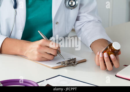 Nahaufnahme der Ärztin Hand halten Sie die Flasche mit Pillen und Rezept zu schreiben. Gesundheitswesen, Medizin und Pharmazie-Konzept. Stockfoto