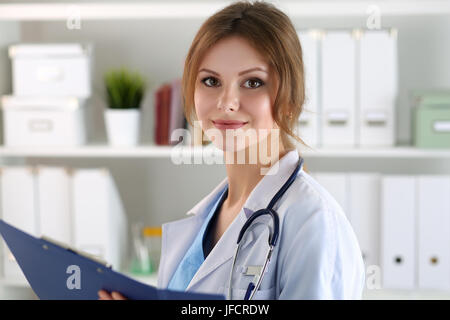 Lächelnde weibliche Medizin Arzt medizinische Anamnese Liste während der Visite ausfüllen. Medizinische Versorgung oder Versicherungskonzept. Arzt bereit zu untersuchen Stockfoto