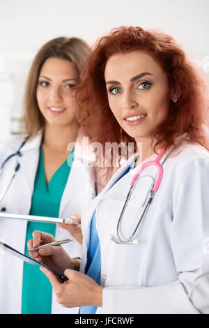Porträt von zwei Ärztinnen stehend mit Zwischenablage und Tablet bereit zu arbeiten. Gesundheitswesen, medizinische Versorgung oder Bildung und Teamwork Konzept. Stockfoto