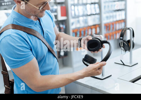 Wow sind sie erstaunlich. Echte Musikliebhaber, die versuchen, ein neues Paar Kopfhörer während herumlaufen und shopping in einem Elektronikfachgeschäft kaufen. Stockfoto
