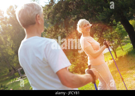 Positive Stimmung. Freudige begeistert ältere Frau lächelnd beim Betrachten ihres Mannes und outdoor-Aktivitäten genießen Stockfoto