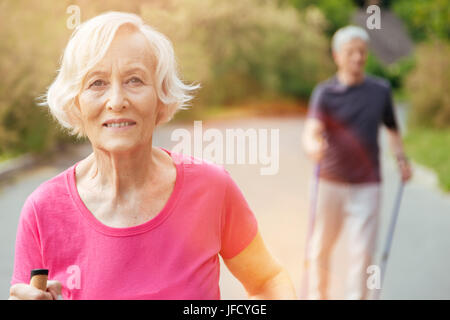 Fröhliches Lächeln. Gerne nette senior Frau betrachten Sie lächelnd bei einem Spaziergang im park Stockfoto