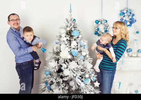 Glückliche Familie von vier Personen (Mutter, Vater, Sohn, Tochter) schmücken Weihnachtsbaum Stockfoto