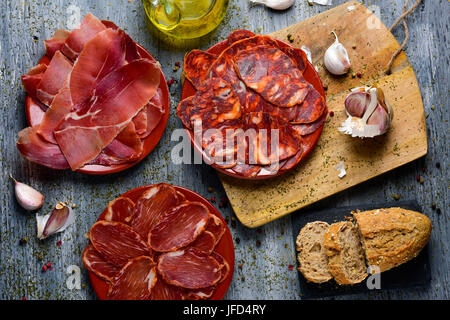 High-Angle Shot einige Platten mit einem Sortiment von verschiedenen spanischen Aufschnitt Chorizo, Filet und Serrano Schinken Wurstwaren, Brot und eine Menage Stockfoto