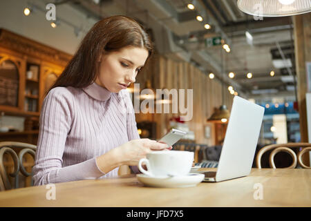 Schöne Brünette mit Laptop im Café. Blogger-Work-Konzept Stockfoto