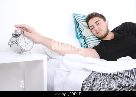 Attraktiver junger Mann mit Wecker. Im Innenbereich. Stockfoto