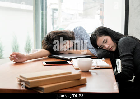 Überarbeitet und müde.  Zwei asiatische Geschäftsfrau schlafen über einen Laptop in einem Schreibtisch bei der Arbeit im Büro. Stockfoto