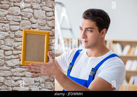 Handwerker setzen Bilderrahmen an der Wand Stockfoto