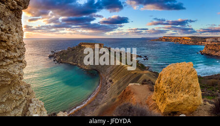 Mgarr, Malta - Panorama von Gnejna und Ghajn Tuffieha Bay, der zwei schönsten Strände auf Malta bei Sonnenuntergang mit schönen bunten Himmel und goldenen Felsen Stockfoto