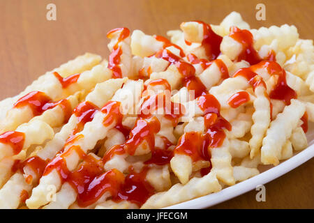 Ein Teller voll mit leckeren Crinkle cut Stil Pommes Frites mit ketchup Stockfoto