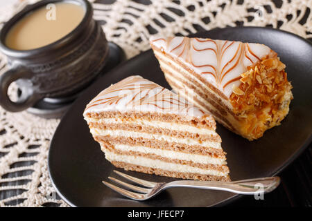 Zwei Stücke von Esterhazy Kuchen auf einen Teller und Kaffee mit Milch Nahaufnahme auf einem Tisch. horizontale Stockfoto