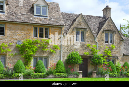 Goldener Honig Steinhäuser mit Vorgärten Formschnitt Pflanzen, Ferienhaus Blumen, Glyzinien, Kletterwand, in einem englischen ländlichen Dorf, an einem sonnigen Stockfoto