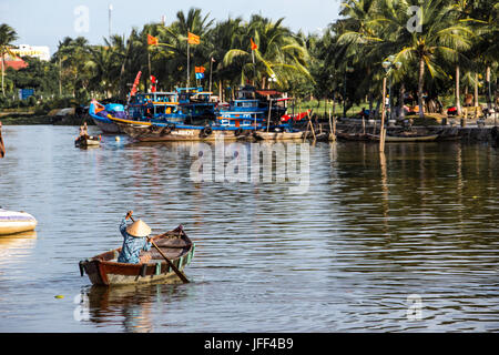 Frau in einem Ruderboot Lookoing für touristische Kunden am Thu Bon Fluss in Hoi an, Vietnam Stockfoto