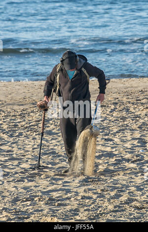 Ein Metalldetektor in den Sand am Strand mit dem Meer im Hintergrund im Hochformat vertikale Suche Stockfoto