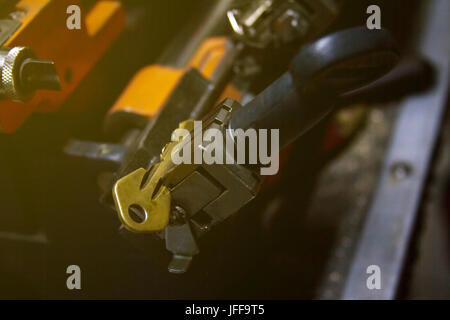 Maschinelle Fertigung von doppelte Metall Schlüssel. Der Schlüssel des gelben Metalls. Stockfoto