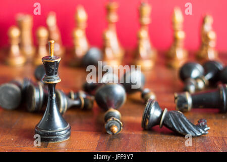 Alte hölzerne Schachfiguren auf einem alten Schachbrett. Auf einem roten Hintergrund. Stockfoto