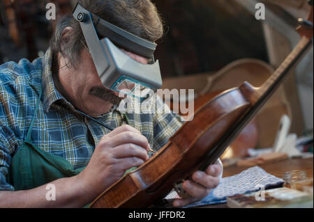 Violin Maker Malerei Violine mit Vergrößerung Stockfoto