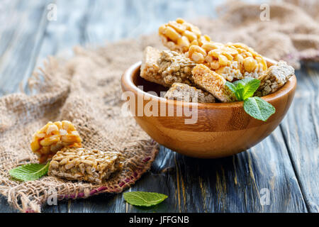 Bars von Honig mit Erdnüssen, Samen und Sesam in eine hölzerne Schüssel. Stockfoto