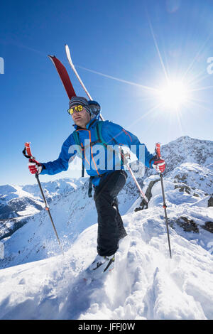 Skifahrer, die zu Fuß nach unten, am Berghang Stockfoto