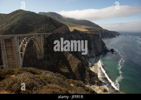 Mehrere Personen sitzen und sightseeing auf Bixby Creek Bridge, eine konkrete, offene Spandrel Bogenbrücke auf dem Pacific Coast Highway. Stockfoto