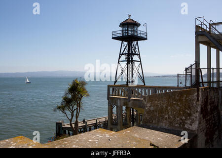 Ein Wachturm auf Alcatraz Island und einen malerischen Blick auf das Wasser und ein Segelboot vor der Küste. Stockfoto